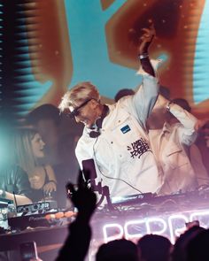 a dj performing at a concert with his arms in the air