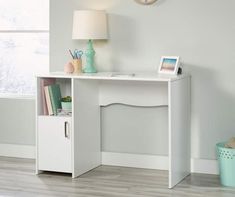 a white desk with a clock on the wall above it and a lamp next to it