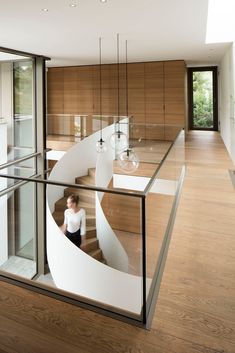 a woman is sitting on the stairs in a room with wood flooring and glass railings