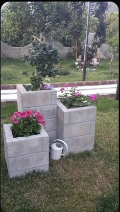 three cement planters sitting in the grass with pink flowers growing out of them,