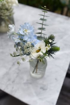 a glass vase filled with flowers sitting on top of a marble slabd table next to a potted plant