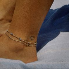 a woman's foot with a small tattoo on her left ankle and a chain around the ankle