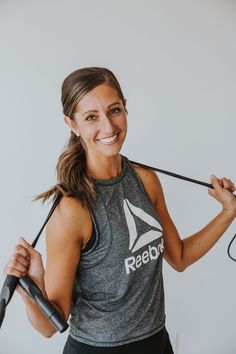 a woman is smiling while holding an exercise rope