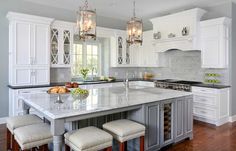 a large kitchen with white cabinets and marble counter tops, an island in the middle