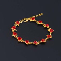 a gold bracelet with red glass beads on a black surface and the clasp is attached to it