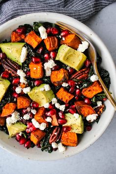 a white bowl filled with sweet potatoes, avocado and pomegranate