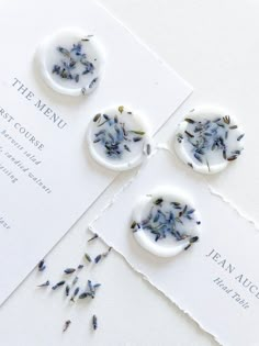 three buttons with dried lavender on them sitting on top of a piece of white paper