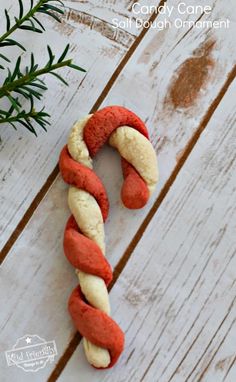 a candy cane is wrapped in red and white icing with a sprig of rosemary