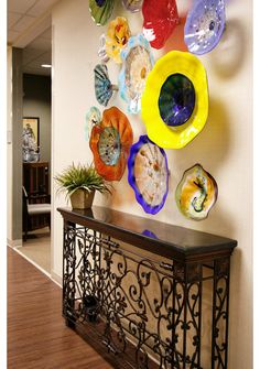 an office hallway decorated with colorful glass plates on the wall, and a console table in front of it