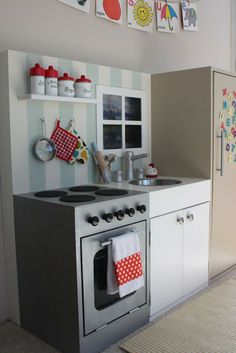 a kitchen with an oven, stove and sink in it's center wall is decorated with children's artwork