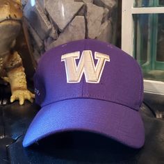 a purple hat with the letter w on it sitting next to a tw statue