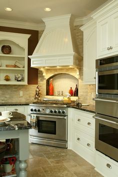 a kitchen with white cabinets and stainless steel stove top oven in the center of the room