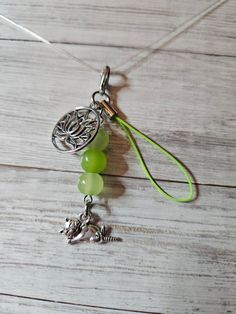 a green beaded necklace with charms hanging from it's side on a wooden surface