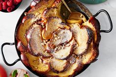 an iron skillet filled with food on top of a white counter next to other plates and bowls