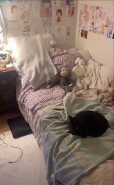 a black cat laying on top of a bed covered in blankets