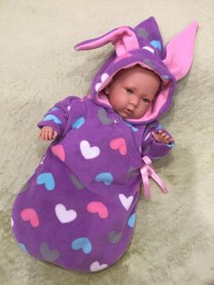 a baby doll that is laying down on the floor wearing a purple outfit with hearts