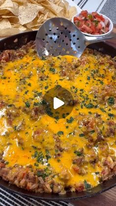 a skillet filled with cheese and tortilla chips on top of a table