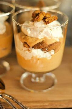 two desserts with whipped cream and cinnamon on top, sitting on a wooden table