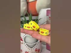 two yellow rubber ducks sitting on top of a persons hand in front of a potted plant