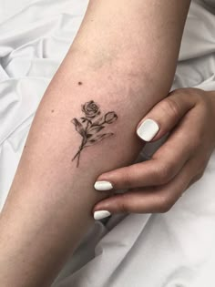 a woman's arm with a small rose tattoo on the left side of her arm