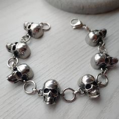 Stunning punk/goth/biker style silver skulls bracelet 💀  Unisex. Made of 100% stainless Steel so will not tarnish or discolour. Available in 2 sizes:  Small: measures 6.5 inches + 1.5 inch extension chain  Large: measures 7.5 inches + 1.5 inch extension chain  Width of bracelet: 20mm Please don't hesitate to contact me with any queries or suggestions or if you require a different size. Comes gift wrapped 🖤 Silver Skull Print Bracelets As A Gift, Gothic Skull Print Bracelets As Gift, Edgy Metal Skull Bracelets, Gothic Stainless Steel Skull Bracelets, Edgy Skull Metal Bracelets, Edgy Skull-shaped Metal Bracelets, Silver Gothic Skull Bracelets, Silver Skull Bracelets In Punk Style, Punk Silver Skull Bracelets