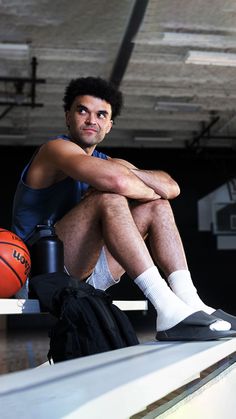 a man sitting on top of a bench next to a basketball