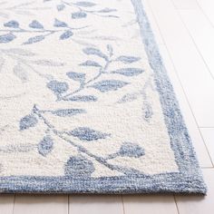 a blue and white rug with leaves on the bottom is laying on a wooden floor