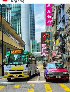 two cars and a bus on a city street with tall buildings in the back ground