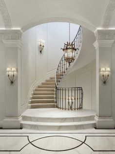 an elegant staircase with chandelier and marble floors