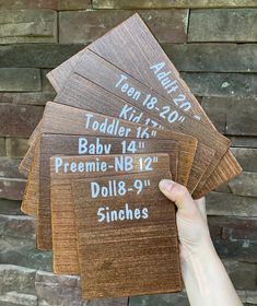 a person holding five wooden signs in front of a brick wall