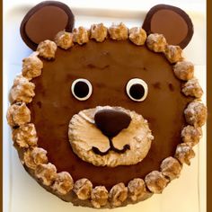 a cake shaped like a bear's head with chocolate icing and nuts on it