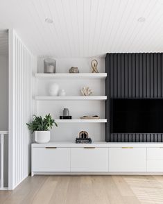 a living room with white shelving and black wall mounted entertainment center in the corner