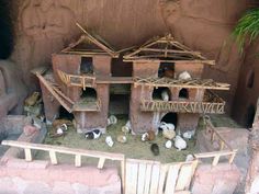 a group of animals that are standing in front of a house made out of clay