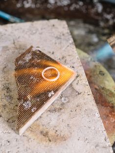 a piece of jewelry sitting on top of a stone slab next to a metal object