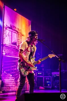 a man standing on top of a stage holding a guitar