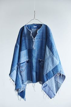 a blue jean jacket hanging on a clothes hanger with holes and fraying around it