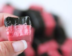 a hand holding up a piece of food with black and pink icing on it