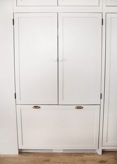 a white cabinet with two doors and drawers on the bottom, next to a wood floor