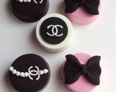 three decorated cookies on a white plate with black and pink icing in the shape of bow ties