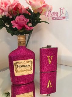 two flasks with pink flowers in them are next to a flask bottle