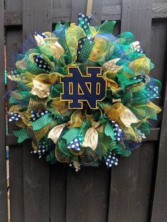 a wreath with the letter n on it hanging on a wooden fence in front of a gate