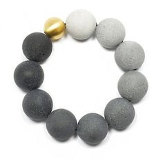 a bracelet made out of gray and white balls with a gold ball on the end