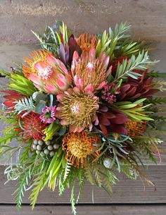 an arrangement of flowers and greenery on a wooden surface