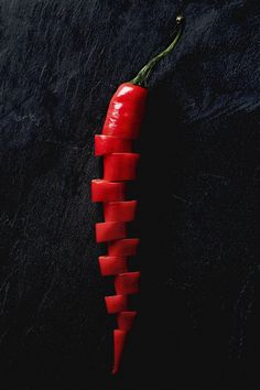 a red pepper sliced in half on a black surface