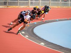 a group of men riding roller blades on top of a track