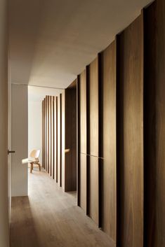 an empty room with wooden slats on the wall and a chair in the corner