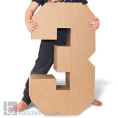 a young boy is posing with a cardboard number 3 sign in front of his face