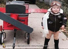 a little boy standing next to a red wagon with a snowboard on it's back