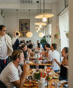 a group of people sitting at a table eating food and drinking drinks in a restaurant