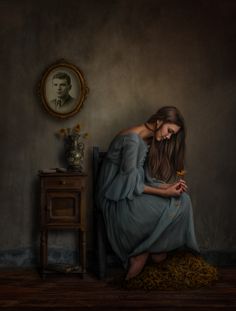 a painting of a woman sitting on a chair in front of a table with flowers